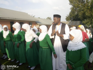 A Man in White Robe and Green Headscarf Addresses Girls